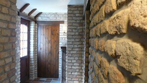 Un couloir en pierre avec une porte en bois et un portail en métal.