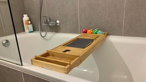 A bathtub with a wooden tray, a handheld showerhead, and colorful bath toys. - 2 bedroom accommodation in Oostduinkerke (Oostduinkerke)