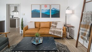 Una sala de estar moderna con un sofá, una mesa de centro y obras de arte en la pared.