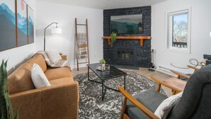 Una sala moderna con chimenea de piedra, un sofá, una mesa de centro y vistas al exterior.