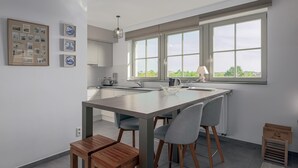 Eine moderne Küche mit Kochinsel, grauen Stühlen und einem Holzschemel.