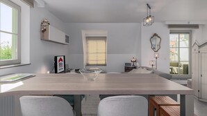 Ein moderner Essbereich mit einem Holztisch, zwei grau gepolsterten Stühlen, einer transparenten Glas-Mitteldekoration und einer Pendelleuchte.