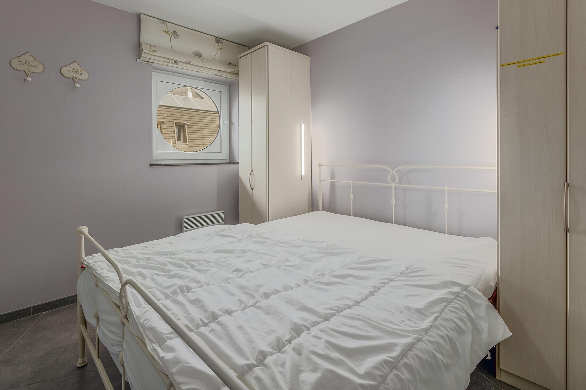 A bedroom with a bed, a wardrobe, a mirror, and wall decorations.