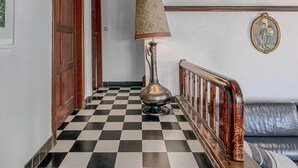Een hal met een geruite vloer, een lamp, een bank en een deur.