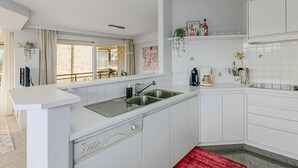 A modern kitchen with white cabinetry, a stainless steel sink, and a red rug. - 2 bedroom accommodation in Oostduinkerke (Oostduinkerke)
