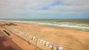 En strand med en rad vita byggnader längs strandlinjen, en sandstrand och havet.