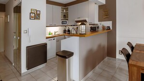 Eine kompakte Küche mit weißen Schränken, einer Mikrowelle, einer Kaffeemaschine und einem kleinen Kühlschrank.