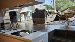 A modern kitchen with a built-in stove, a dining area with a sofa and chairs, and a view of the outdoors. - 2 bedroom accommodation in Oostduinkerke (Oostduinkerke)
