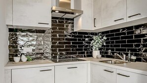 Una cocina moderna con armarios blancos, un salpicadero negro y una campana extractora de acero inoxidable.