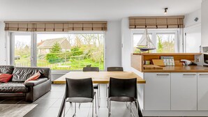 Eine moderne Küche mit Essbereich, großen Fenstern und Blick auf den Garten.