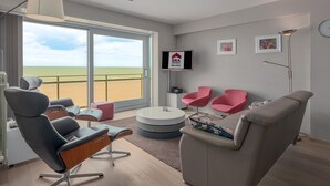 A modern living room with a large window, a round coffee table, a sofa, and two pink chairs. - 4 bedroom accommodation in Sint Idesbald (Sint Idesbald)