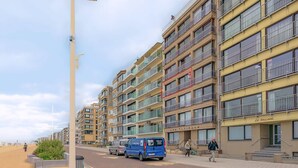 A multi-story residential building with balconies, a streetlight, and a van parked in front. - 4 bedroom accommodation in Sint Idesbald (Sint Idesbald)