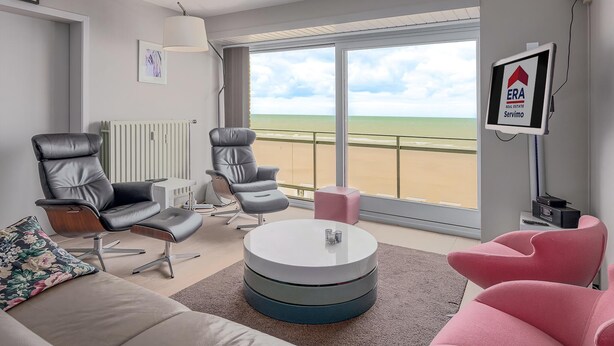 A modern living room with a large window overlooking a beach, a round coffee table, and two leather chairs. - 4 bedroom accommodation in Sint Idesbald (Sint Idesbald)