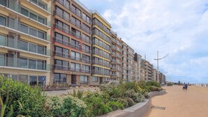 A multi-story residential building with balconies, a paved walkway, and a beach in the background. - 4 bedroom accommodation in Sint Idesbald (Sint Idesbald)