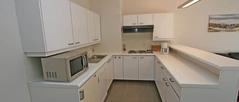 A compact kitchen with white cabinets, a microwave, and a sink.
