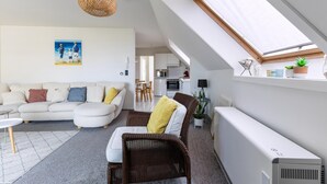 Ein modernes Wohnzimmer mit einer Couch, einem Korbstuhl und einem Essbereich.