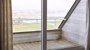 Ein Balkon mit Blick auf eine Stadtlandschaft, Holzboden und Metallgeländer.