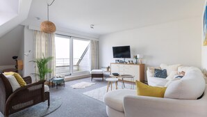 Ein modernes Wohnzimmer mit einer Couch, einem Esstisch und einem Fernseher.