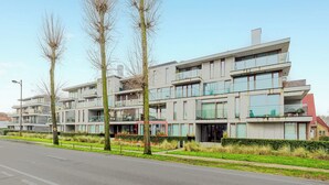 A modern multi-story residential building with balconies, large windows, and a well-maintained lawn. - 3 bedroom accommodation in Oostduinkerke (Oostduinkerke)