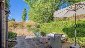 A wooden deck with outdoor furniture, including a chair, a sofa, and an umbrella. - 4 bedroom accommodation in Oostduinkerke (Oostduinkerke)