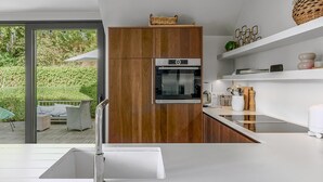 A modern kitchen with a built-in oven, white countertops, and wooden cabinets. - 4 bedroom accommodation in Oostduinkerke (Oostduinkerke)