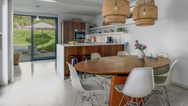 A modern kitchen with a wooden dining table, white chairs, and wicker pendant lights. - 4 bedroom accommodation in Oostduinkerke (Oostduinkerke)