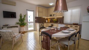 A dining area with a table set for four, a potted plant, and a television on the wall. - Apartment Zvone (Supetar)