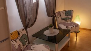 A small, cozy room with a table and two chairs, a potted plant, and a green lamp. - Apartment Zvone (Supetar)
