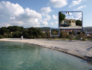 Uma área costeira com uma praia limpa, um edifício com telhado vermelho e um carro estacionado em frente.