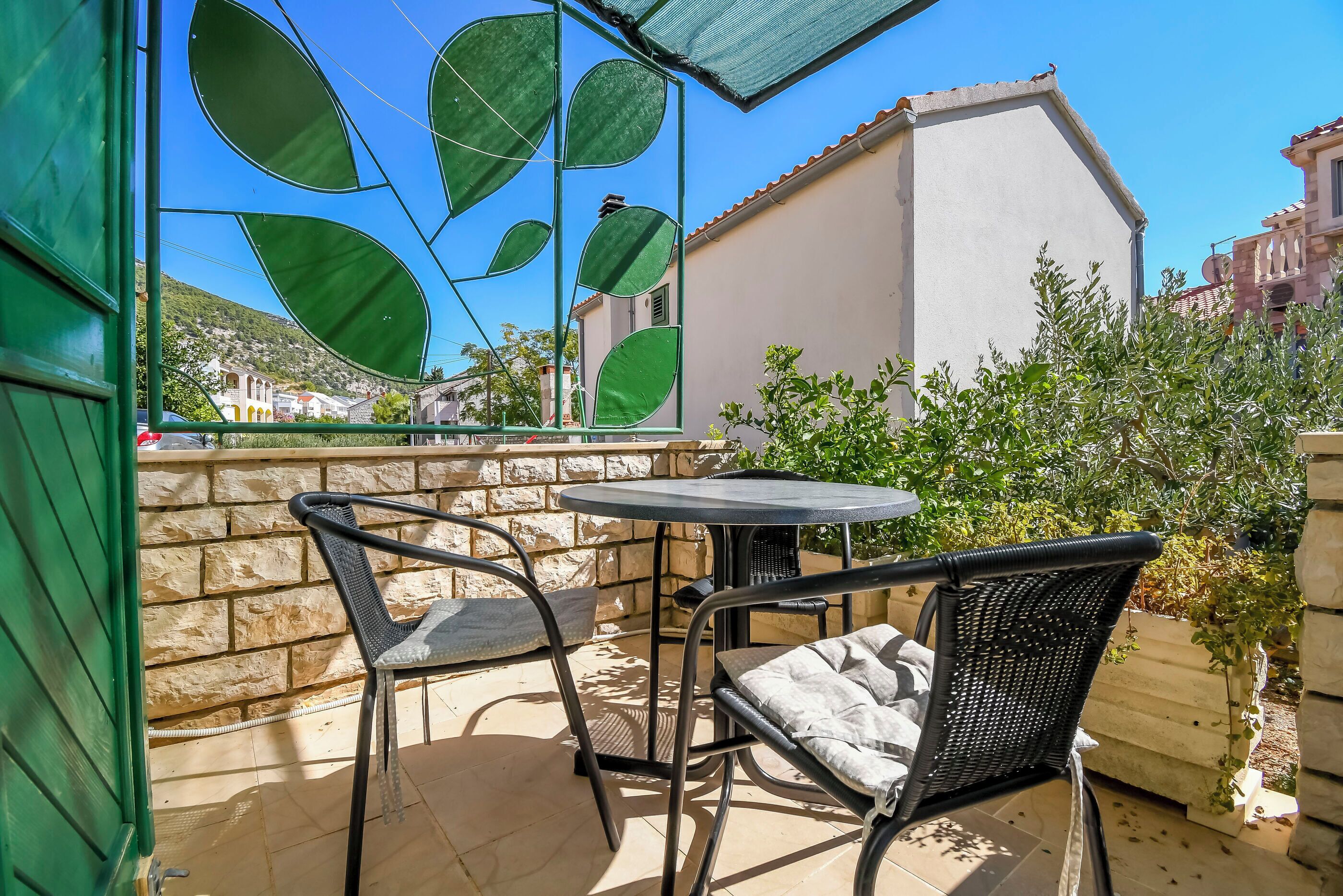 An outdoor patio with a table and chairs, a stone wall, and a view of a hillside.