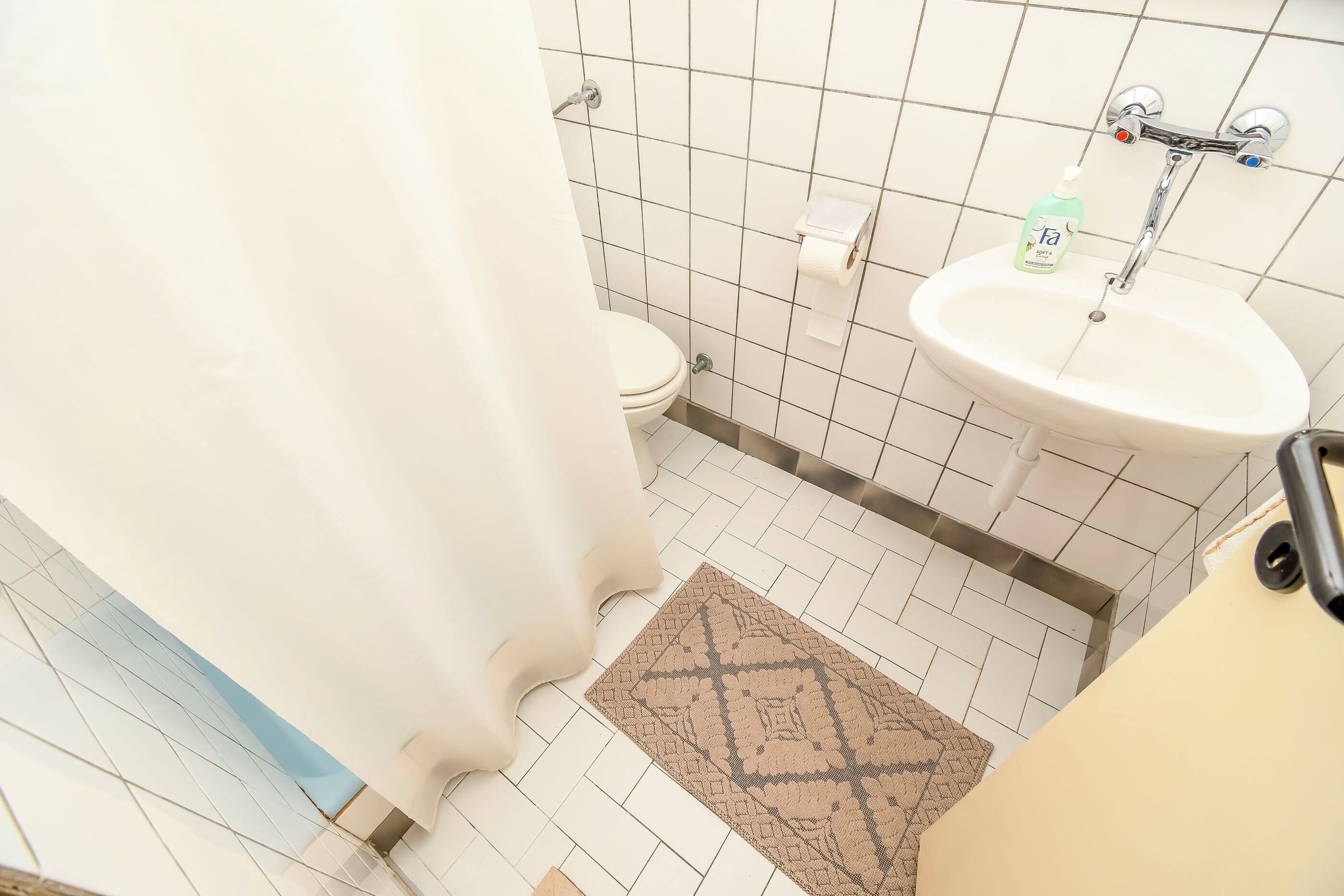 Un baño con inodoro, lavamanos y cortina de ducha.