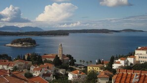 A coastal town with a prominent church tower, a small island, and a clear view of the sea. - Apartments Sto (Hvar)