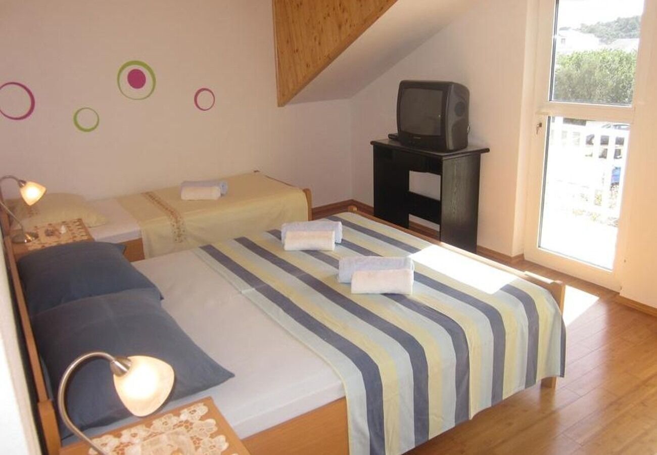 A bedroom with two beds, a TV, and a window.