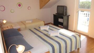 A bedroom with two beds, a TV, and a window.