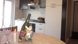 A kitchen with white cabinets, a stainless steel range hood, and a dining table with wine glasses and a candle. - Apartments Sto (Hvar)
