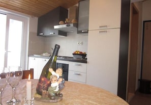 Ett kök med ett matbord dukat för två personer, en flaska vin och ett ljus.