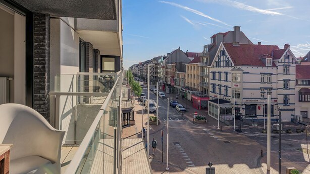 A balcony with a view of a street lined with traditional European buildings, a clear sky, and a few pedestrians. - 2 bedroom accommodation in Nieuwpoort (Nieuwpoort)