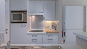 A modern kitchen with white cabinetry, a built-in microwave, a coffee maker, and a double sink. - 2 bedroom accommodation in Nieuwpoort (Nieuwpoort)