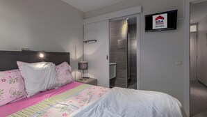 A bedroom with a bed, a nightstand, a lamp, a closet, and a television displaying a real estate sign. - 2 bedroom accommodation in Nieuwpoort (Nieuwpoort)