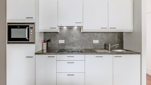 A modern kitchen with white cabinets, a built-in microwave, a gas stove, and a sink. - 3 bedroom accommodation in Nieuwpoort (Nieuwpoort)
