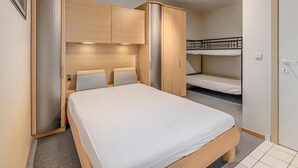A bedroom with a single bed, wooden wardrobe, and a bunk bed.