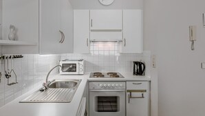 A modern kitchen with white cabinetry, a built-in oven, a microwave, and a coffee maker.