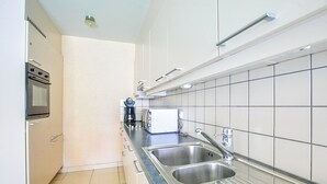 Eine moderne Küche mit Edelstahlgeräten, einer Spüle und weiß gefliesten Wänden.