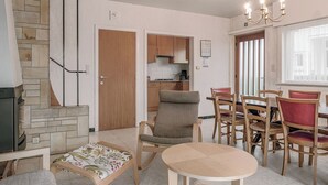 A living room with a fireplace, a dining area with wooden chairs, and a kitchen visible through an open door. - 5 bedroom accommodation in Koksijde (Koksijde)