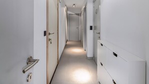 A modern hotel hallway with white walls, a tiled floor, and a series of doors leading to rooms. - 2 bedroom accommodation in Oostduinkerke (Oostduinkerke)