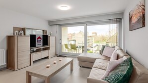 A modern living room with a sofa, a coffee table, and a TV on a wooden cabinet. - 2 bedroom accommodation in Oostduinkerke (Oostduinkerke)