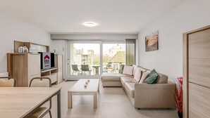 A modern living room with a sofa, a dining table, and a kitchen area. - 2 bedroom accommodation in Oostduinkerke (Oostduinkerke)