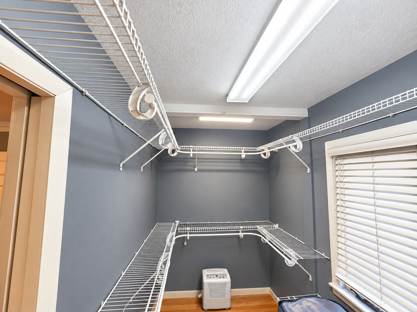 A laundry room with a ceiling fan, a heater, and a window with blinds.