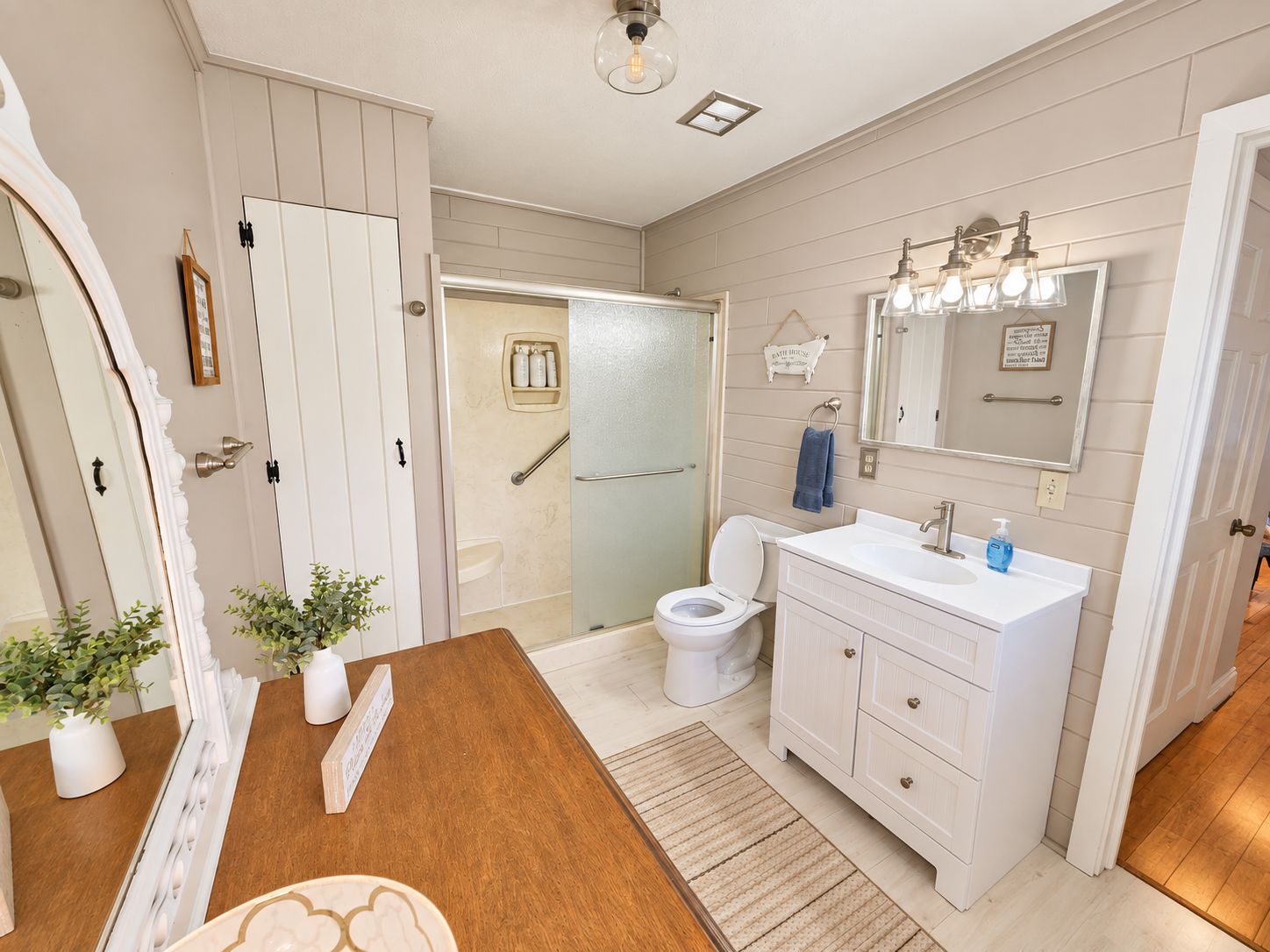 A bathroom with a white vanity, a toilet, and a shower area.