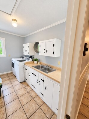 A laundry room with a washing machine, dryer, and a sink.